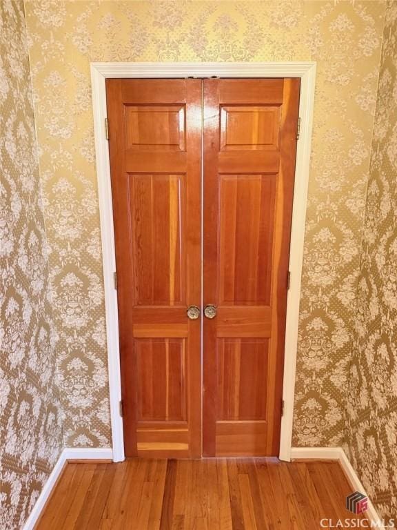 details with baseboards, wallpapered walls, and wood finished floors