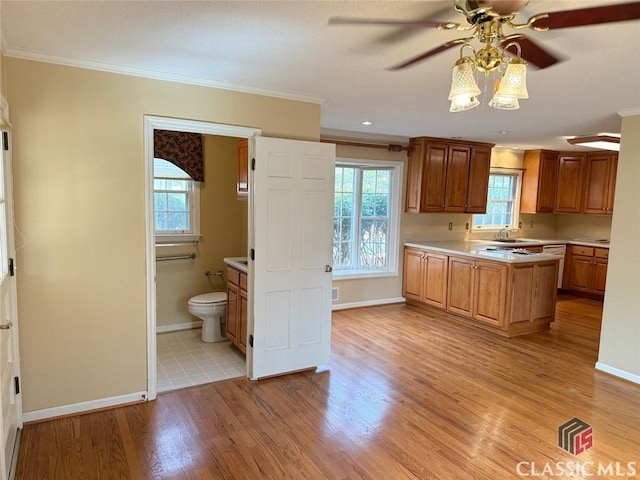 kitchen with light countertops, ornamental molding, a sink, and light wood-style flooring