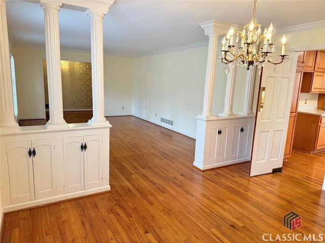 unfurnished dining area featuring a notable chandelier, crown molding, light wood finished floors, baseboards, and visible vents
