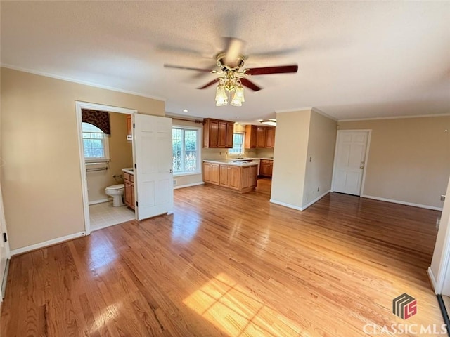 unfurnished living room featuring light wood finished floors, baseboards, a ceiling fan, and ornamental molding