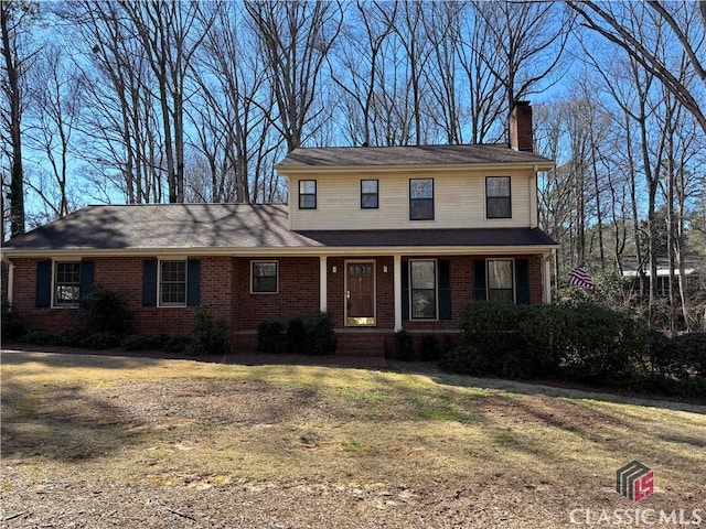 view of front of property featuring a chimney and brick siding