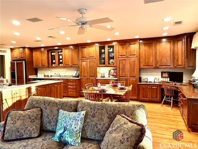 kitchen featuring visible vents, brown cabinetry, built in study area, light wood-style flooring, and paneled fridge