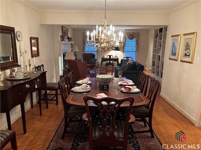 dining area with ornamental molding, a notable chandelier, baseboards, and wood finished floors