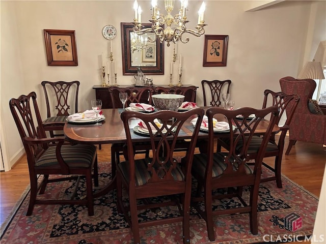 dining space featuring a chandelier, baseboards, and wood finished floors