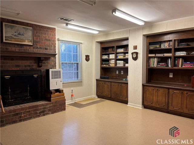 interior space with built in shelves, a brick fireplace, heating unit, light floors, and crown molding