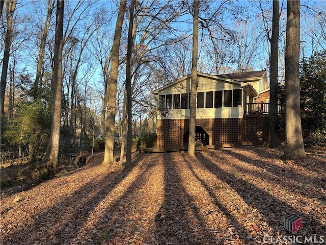 view of home's exterior featuring a sunroom and dirt driveway