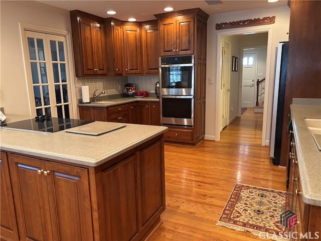 kitchen with light wood-style flooring, black electric cooktop, double oven, backsplash, and recessed lighting