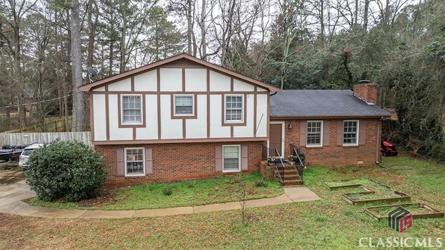 view of front facade featuring brick siding, fence, roof with shingles, a front lawn, and a chimney