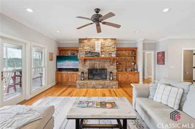 living room featuring light wood-style flooring, a fireplace, and crown molding