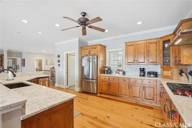 kitchen featuring light stone counters, appliances with stainless steel finishes, a sink, and glass insert cabinets