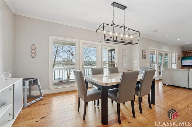 dining room featuring ornamental molding, light wood-style flooring, baseboards, and an inviting chandelier