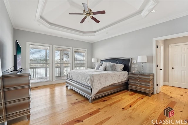 bedroom featuring light wood-style flooring, ceiling fan, access to exterior, a tray ceiling, and crown molding