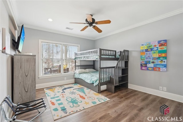 bedroom with ornamental molding and wood finished floors