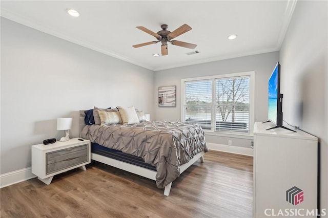 bedroom featuring ornamental molding, visible vents, baseboards, and wood finished floors