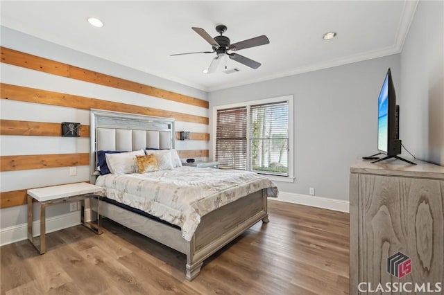 bedroom featuring ornamental molding, visible vents, baseboards, and wood finished floors