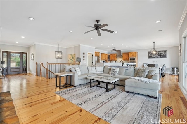 living room featuring crown molding, recessed lighting, light wood-style flooring, an inviting chandelier, and baseboards