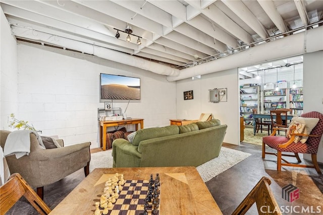 living area with concrete flooring and concrete block wall