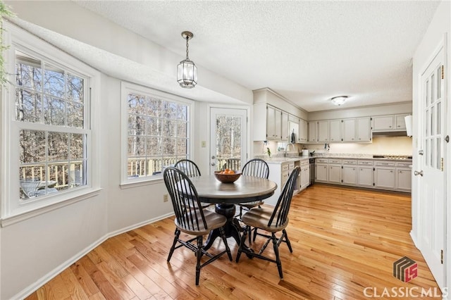 dining space with light wood-style floors, baseboards, and a textured ceiling