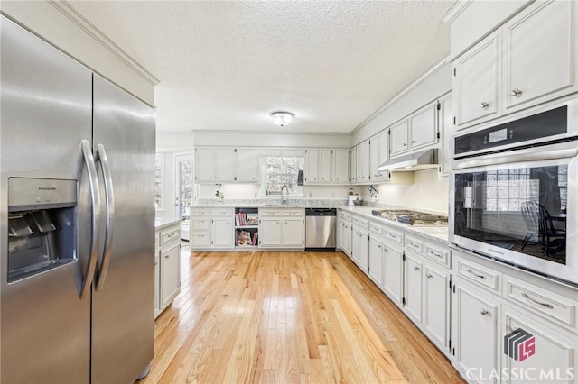 kitchen featuring stainless steel appliances, a sink, white cabinetry, and under cabinet range hood