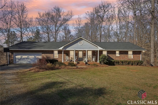 ranch-style home featuring a garage, brick siding, driveway, and a lawn