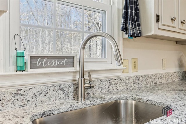 room details featuring a sink and light stone countertops