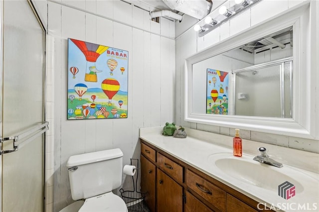 full bathroom featuring toilet, vanity, and a shower with shower door