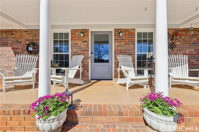 property entrance with covered porch and brick siding