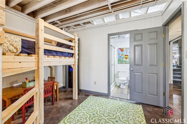 bedroom featuring concrete flooring, ensuite bath, and baseboards