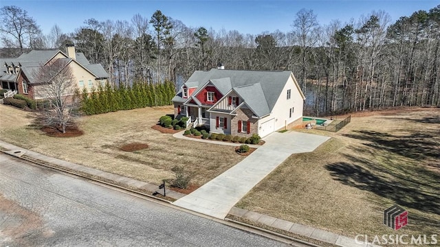 view of front of home featuring driveway, a forest view, and a front yard