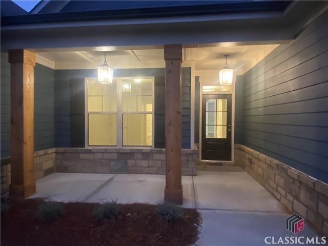 view of exterior entry featuring stone siding and a porch