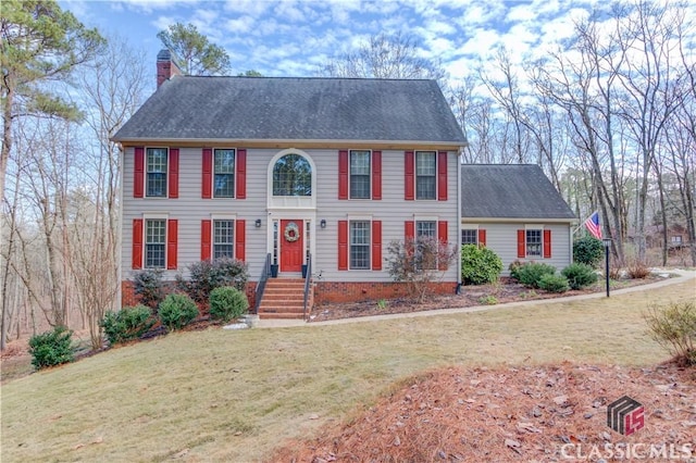 colonial-style house featuring a front lawn, a chimney, and a shingled roof