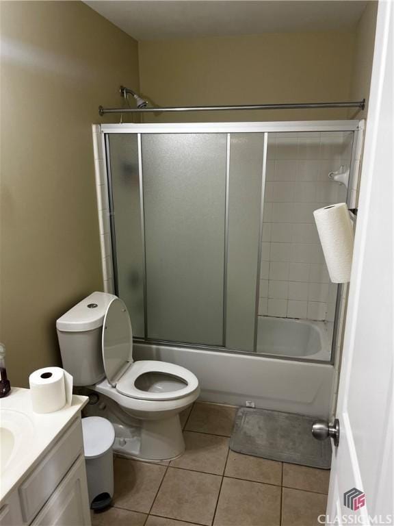 bathroom with toilet, shower / bath combination with glass door, tile patterned flooring, and vanity