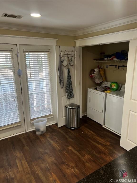 laundry area with dark wood-style floors, crown molding, washing machine and clothes dryer, visible vents, and laundry area