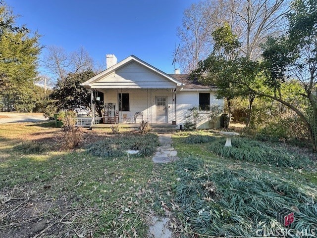 view of front of house with a chimney, a porch, and a front yard