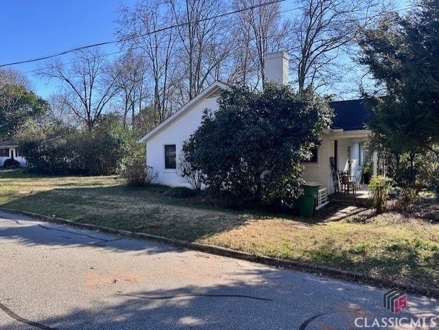 view of side of home with a lawn and a chimney