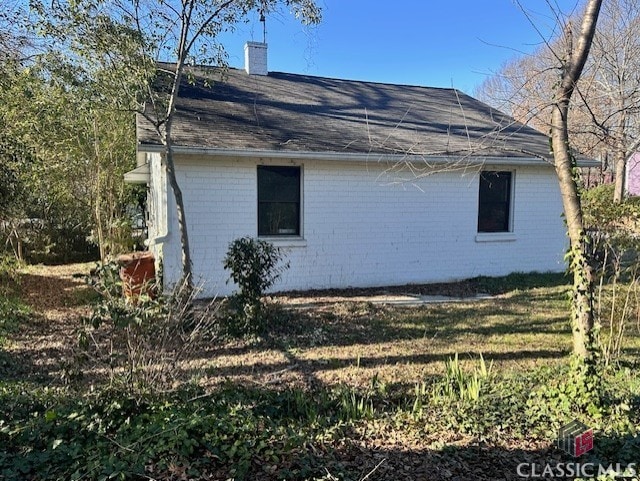 view of property exterior featuring a chimney and brick siding