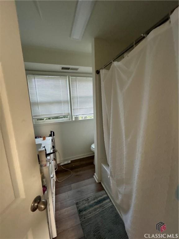 full bathroom with shower / bath combination with curtain, visible vents, toilet, wood finished floors, and baseboards