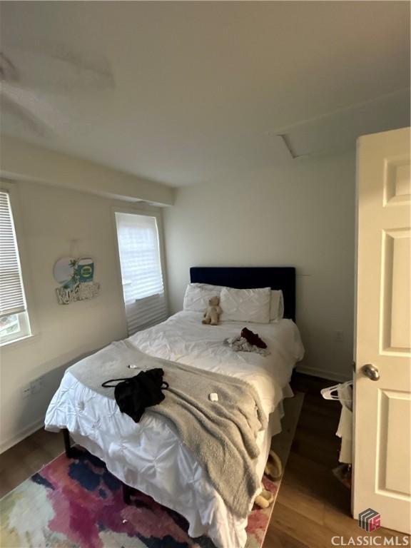 bedroom featuring attic access, baseboards, and dark wood-style flooring