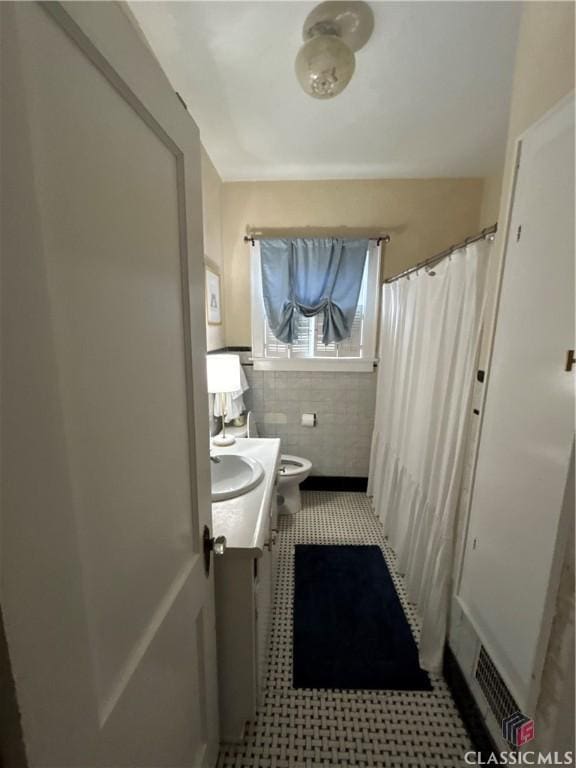 full bathroom featuring toilet, vanity, and tile walls