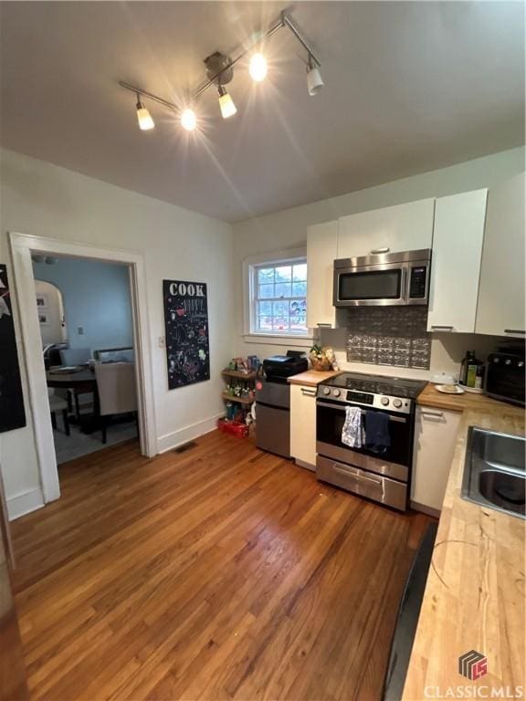 kitchen with decorative backsplash, dark wood-type flooring, stainless steel appliances, white cabinetry, and a sink