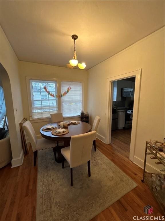 dining area with arched walkways, baseboards, dark wood finished floors, and lofted ceiling