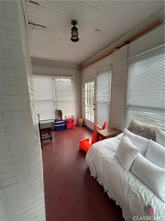 bedroom featuring finished concrete flooring, brick wall, and crown molding