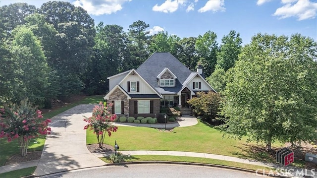 craftsman house featuring stone siding, a front lawn, and concrete driveway