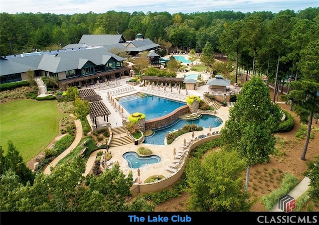 pool with a patio area and a view of trees