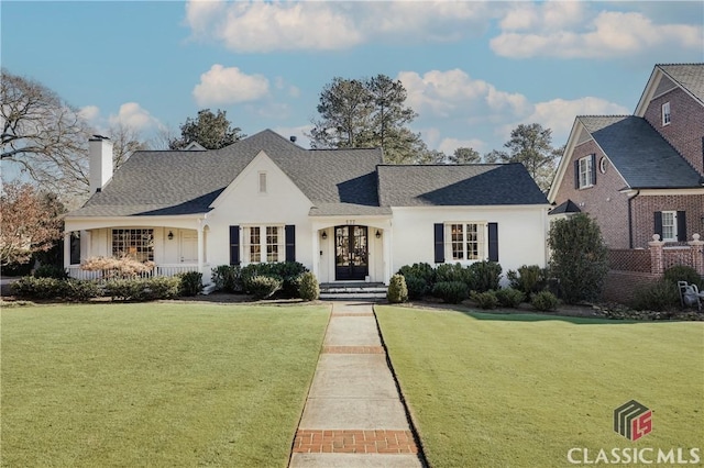 view of front of home featuring roof with shingles, a front lawn, and stucco siding