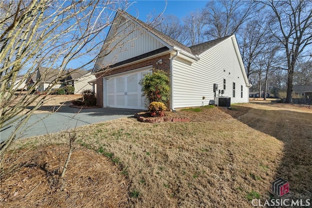 view of home's exterior featuring an attached garage, central AC, brick siding, driveway, and a lawn