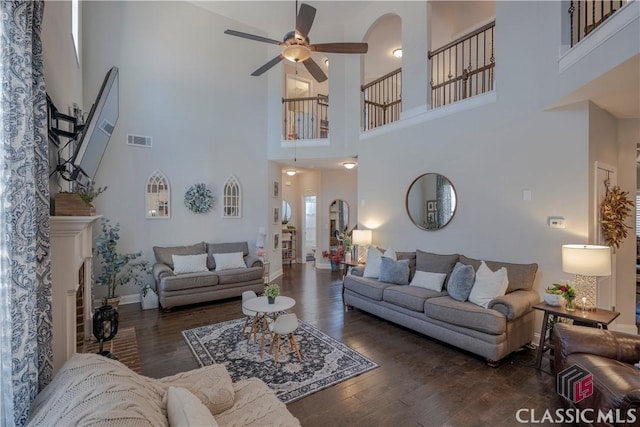 living room featuring a ceiling fan, baseboards, visible vents, and wood finished floors