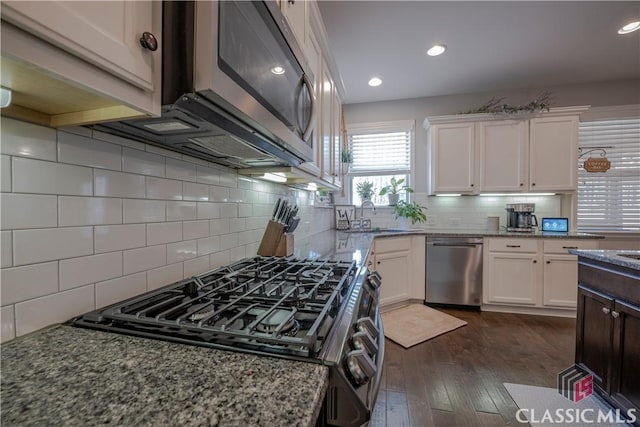 kitchen featuring stainless steel appliances, a sink, white cabinetry, and light stone countertops