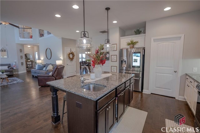 kitchen featuring dark wood-style floors, a breakfast bar, a sink, dark brown cabinets, and stainless steel fridge with ice dispenser