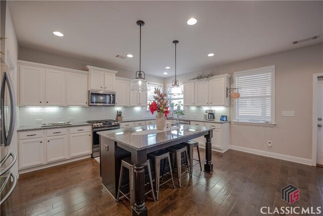 kitchen with dark wood-style floors, stainless steel appliances, backsplash, and white cabinets